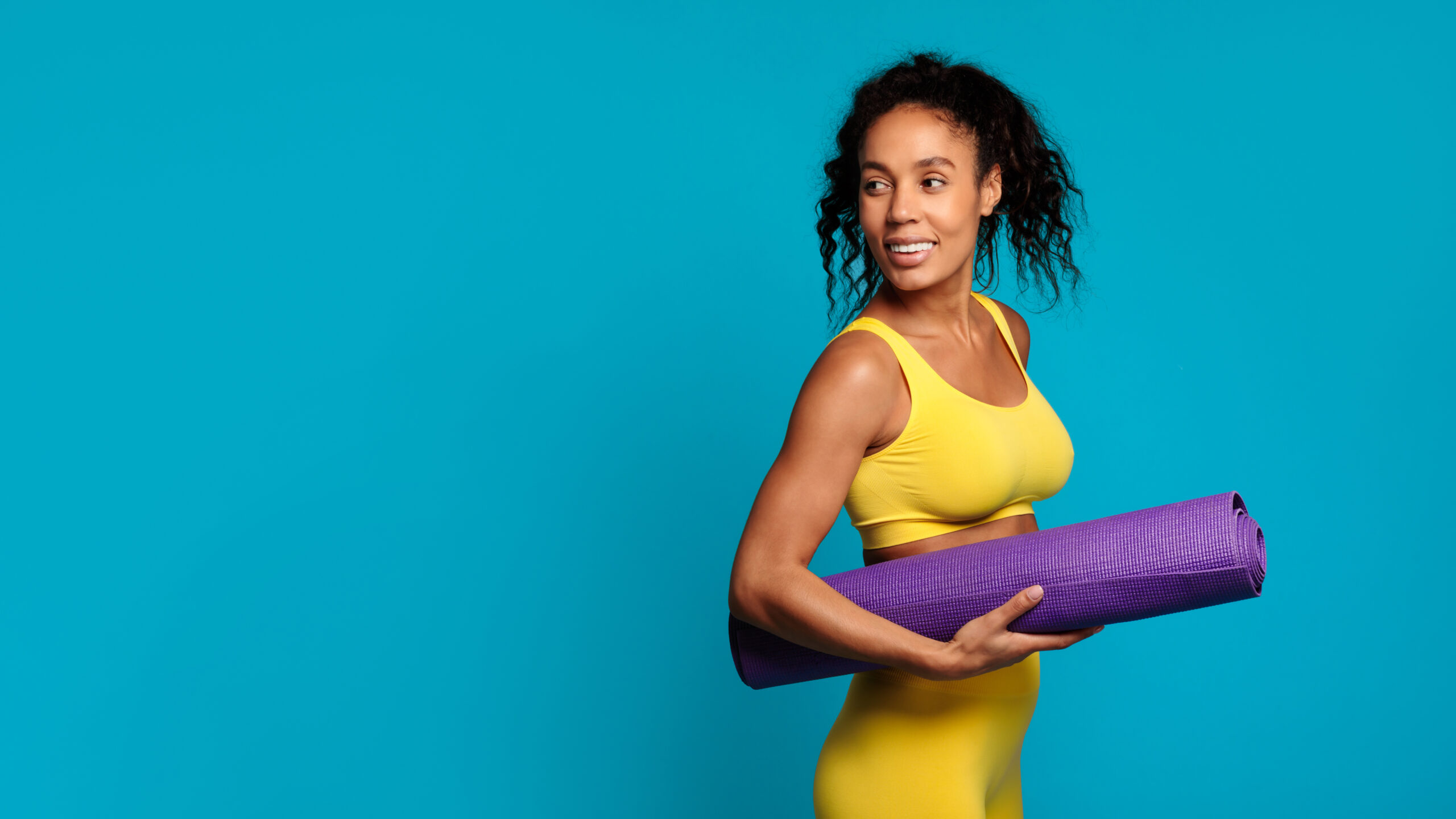 Happy woman holding a yoga mat